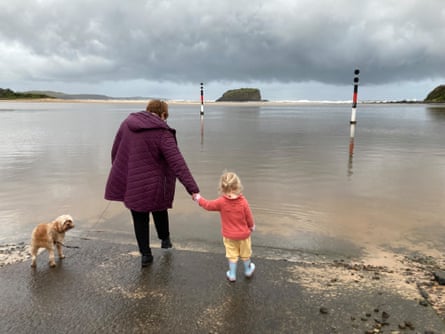 Chien, femme et fille debout sur la plage le jour de la pluie