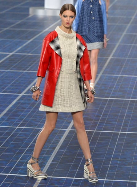 Lindsey Wixson modelling a beige mini dress and red coat on a catwalk