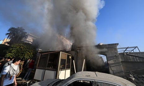 People check the damage as smoke billows from a building hit by a reported Israeli strike in the Mazzeh district of Damascus.