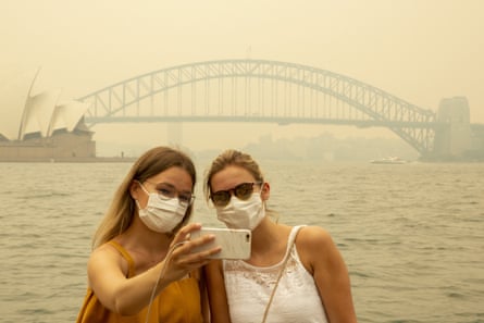 German tourists Julia Wasmiller and Jessica Pryor take a selfie at Mrs Macquarie’s chair, wearing face masks due to heavy smoke on 19 December.