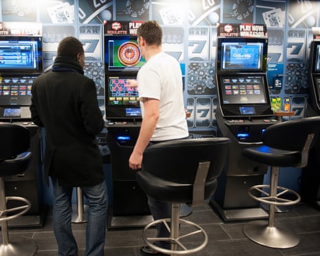 Two men try out gaming machines at a William Hill betting shop.