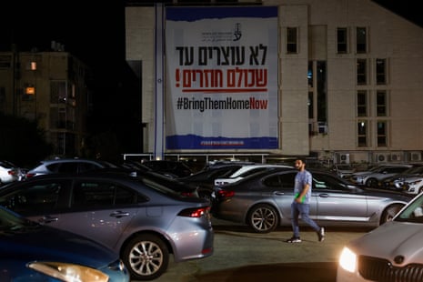 A man walks past a ‘bring them home now’ sign in support of hostages kidnapped in 7 October Hamas attack on Israel, in Tel Aviv on Wednesday evening.