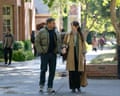A man and a woman walk through a leafy college campus together.