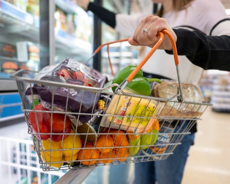 A woman holds a basket of goods in a supermarket, May 2022 in Cardiff, Wales