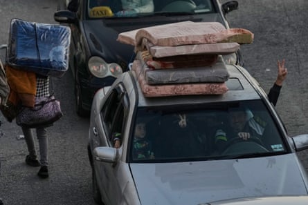 A family flashes victory signs as they flee Israeli airstrikes in Dahiyeh, Beirut's southern suburbs