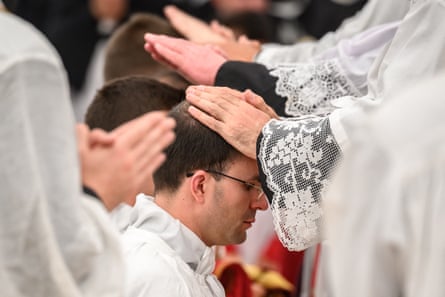 Hands being put on heads of kneeling priests