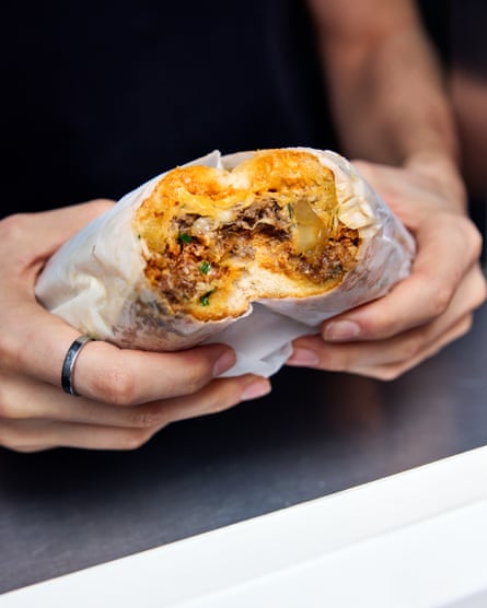 A man holding a sandwich, with a bite taken out of it