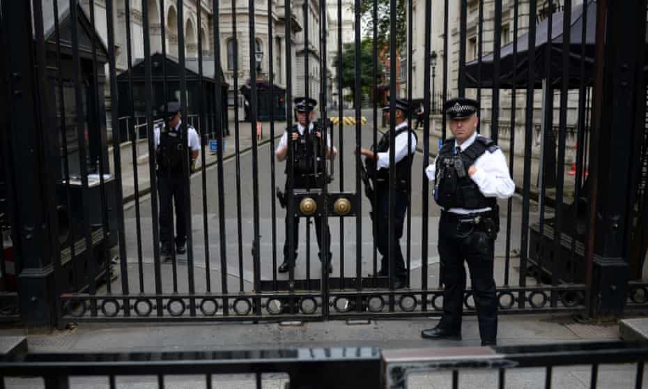 armed police officers behind the gates of downing street