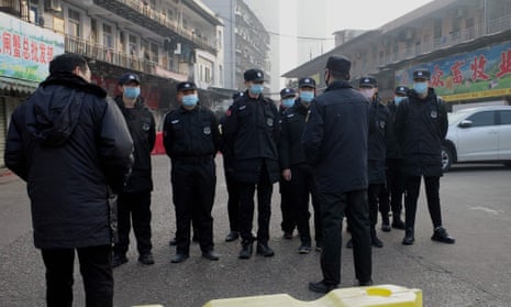 Security guards outside the Huanan wholesale seafood market in Wuhan, central China, where health authorities say the man who died from the new coronavirus had bought food. 