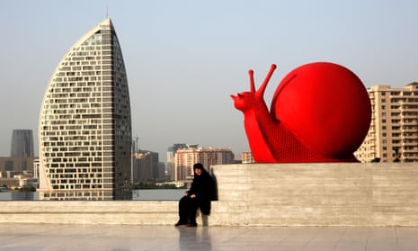 A woman sits by a sculpture of a snail near the Heydar Aliyev Cultural Centre ahead of the first European Games in Baku.
