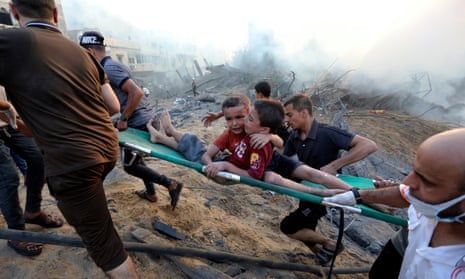 Palestinians evacuate two wounded boys following Israeli airstrikes on Gaza City on 25 October.