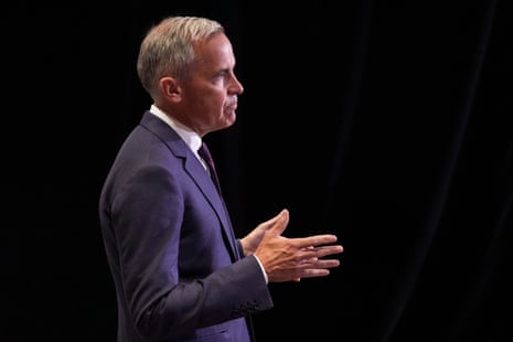 viewed from the side, a man in a suit speaks with his hands in front of him