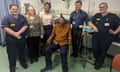 Elliot Pfebre sitting on chair surrounded by smiling hospital staff