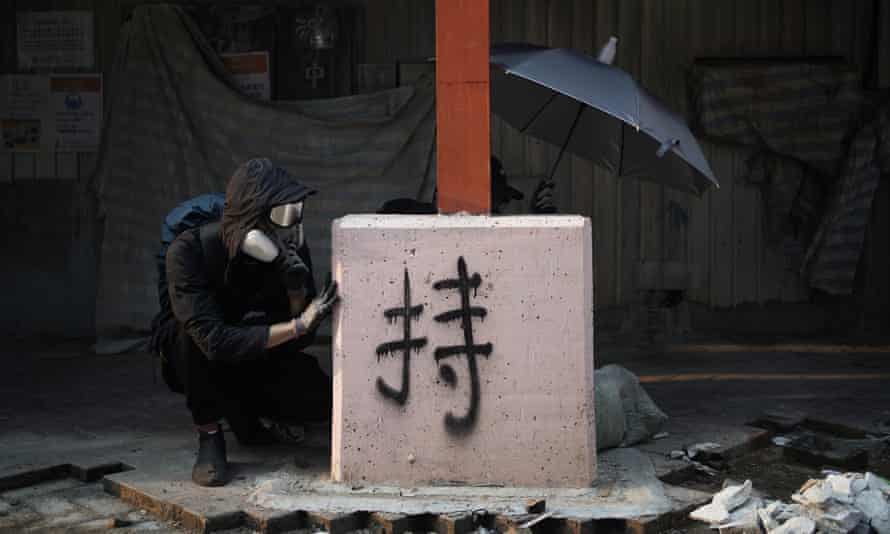 Protesters take cover during a confrontation with police in Hong Kong, 20 October.