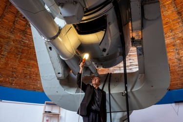 Henrik Sargsyan holds a lamp up to part of a large telescope