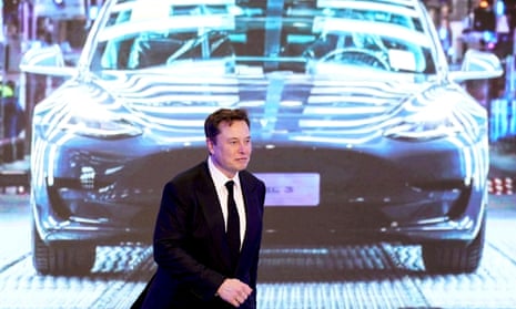 Tesla CEO Elon Musk walks next to a screen showing an image of a Tesla Model 3 car in Shanghai, China, in 2020