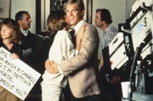 Two people hug in front of TV cameras.