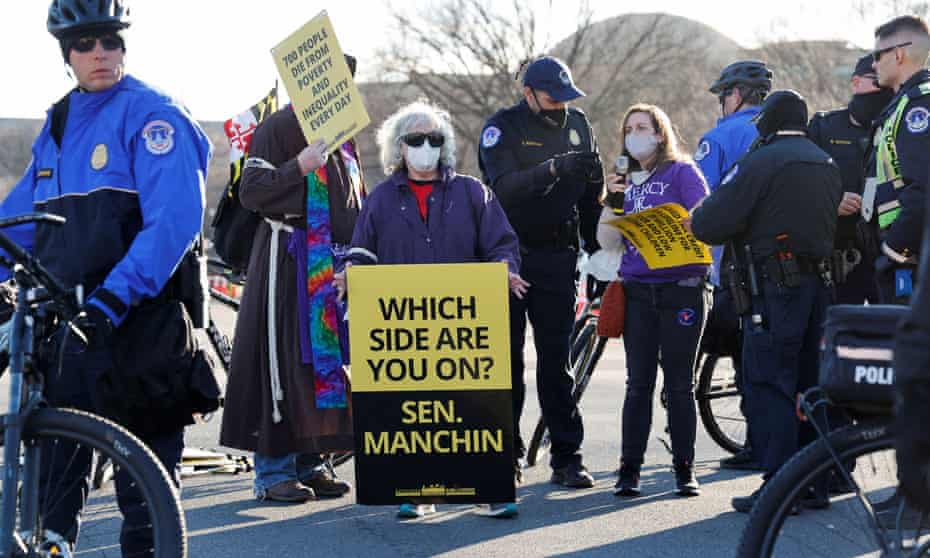 A woman holds a sign reading "Which side are you on? Sen Manchin" during a protest.