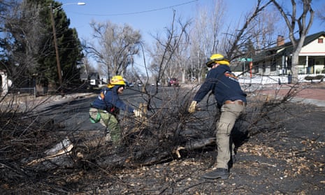Two Colorado Springs Utilities crew members pull a fallen tree out of a street after a wind storm.