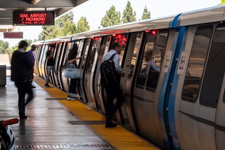 Commuters board a BART train at Fremont station as doors show red warning lights