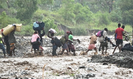 People cross the La Digue river in Haiti during heavy rain