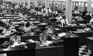 Lots of desks and office workers in an office in the 1950s
