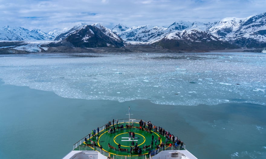 Cruise ship sailing to a glacier with pass support on the ship's helipad, looking at a huge iceberg.