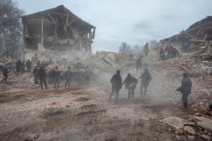 People remove debris at the site of a military base in Okhtyrka.