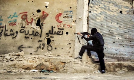 A fighter is seen in the Qaban neighborhood of Damascus shooting from around a corner.