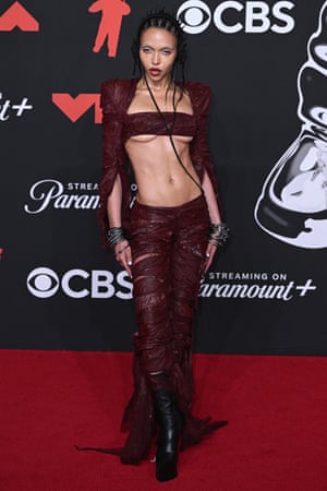 FKA twigs wears a burgundy shawl with her braids styled to resemble a pair of headphones.