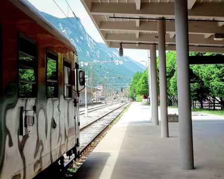 Train pulling away from station towards mountains