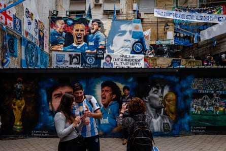 I visitatori scattano selfie nella piazza sotto il murale, che è ricoperto da murales più piccoli di Maradona.