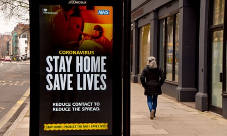 A woman walks past a ‘Stay Home Save Lives’ sign in Central London