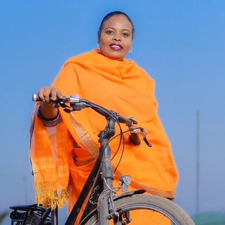 A woman wearing bright orange wheels a black bicycle