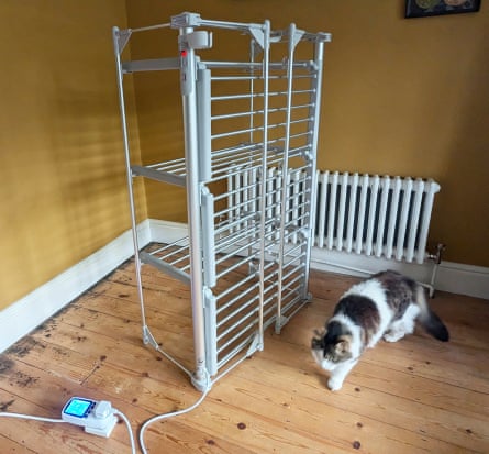 Soon Deluxe 3-tier heated clothes airer in a ochre room with a wooden floor. A tan and white cat walks past the airer