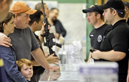 A family, including a young boy, stands at a counter to look at firearms at a gun shop in Fort Worth, Texas.