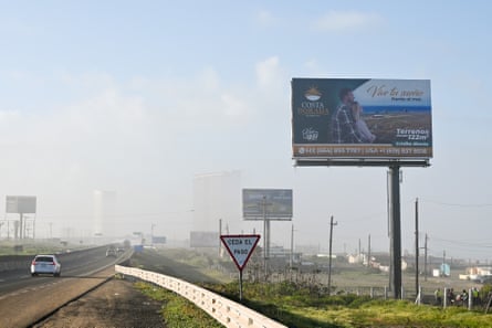 A view from a car of roadside billboards rising from a grassy verge.