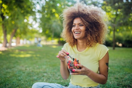Portrait of black woman sitting at the park, eating fruits and enjoying.