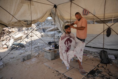 Palestinian barber Mousa al-Kharibi gives a man a haircut inside a tent in Khan Younis.