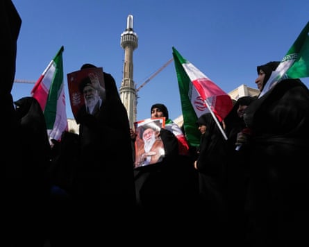 Women hold up Iranian flags and pictures of Ali Khamenei