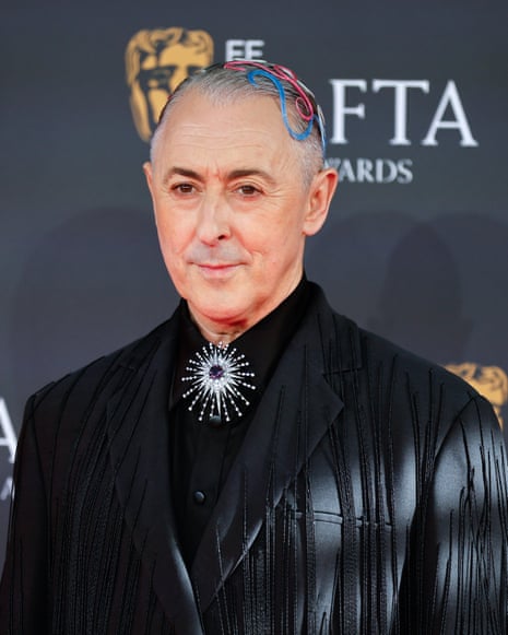 Alan Cumming with hair accessories and a black jacket