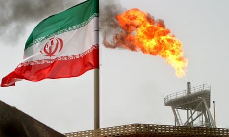 A gas flare on an oil production platform alongside an Iranian flag