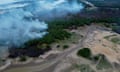 An aerial view of a fire in the Amazon rainforest with smoke rising from the jungle.