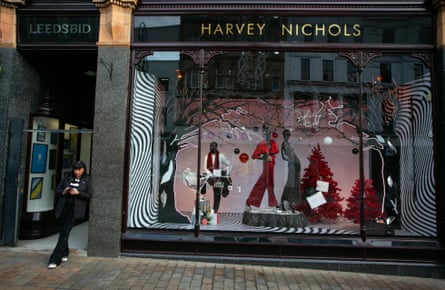 A woman on her phone beside the Harvey Nichols Christmas shop window display in Leeds city centre in West Yorkshire