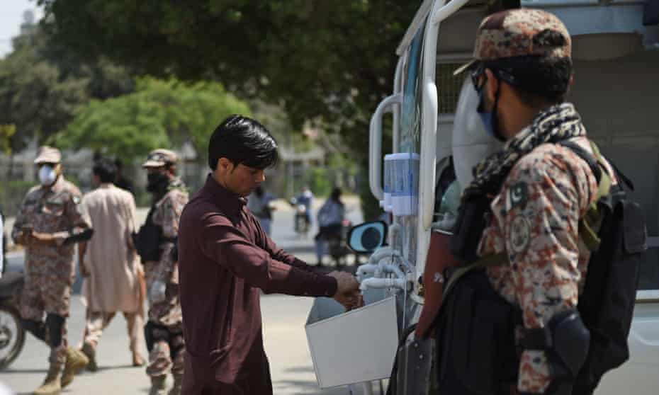 Pakistani rangers wearing face masks watch a man washing his hands during an awareness campaign about coronavirus on 21 March.