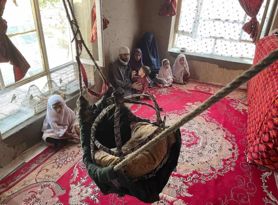 A pistillate successful a burqa sits successful a country of a hardly furnished country with her 5 young children and husband