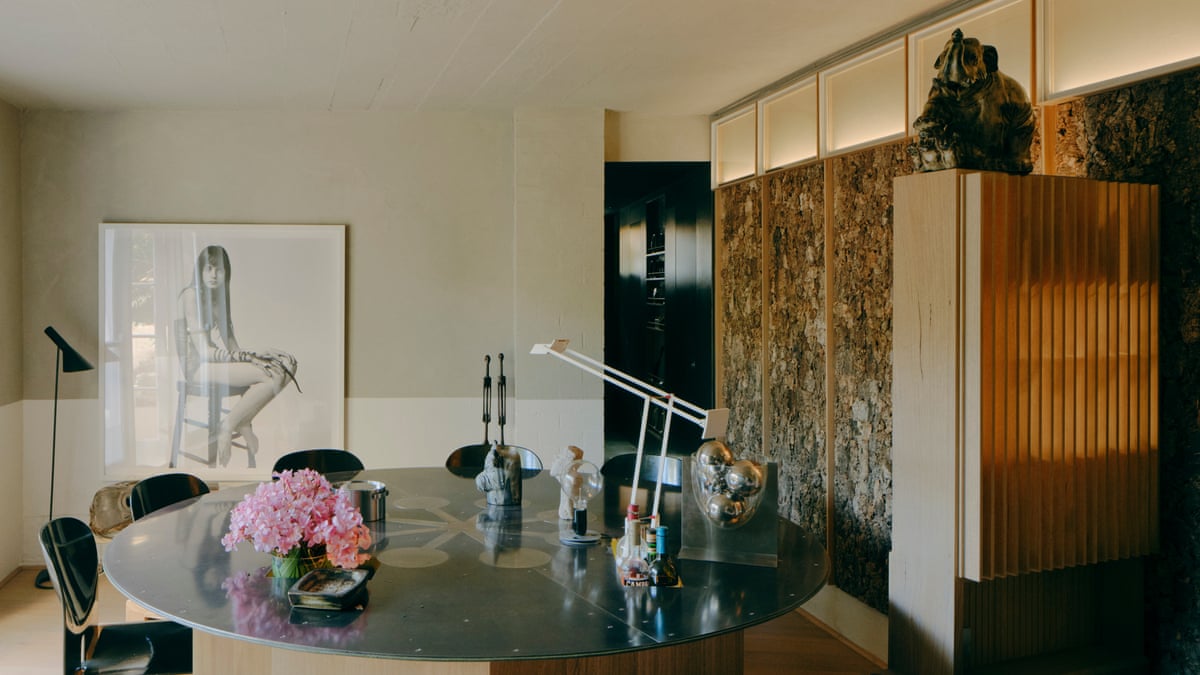 A round table with flowers sits before a framed photo of a seated woman