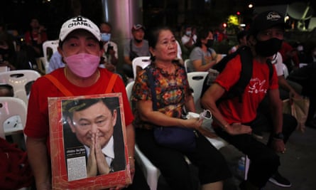 A Pheu Thai supporter holds a portrait of Thaksin Shinawatra at the party’s headquarters in Bangkok