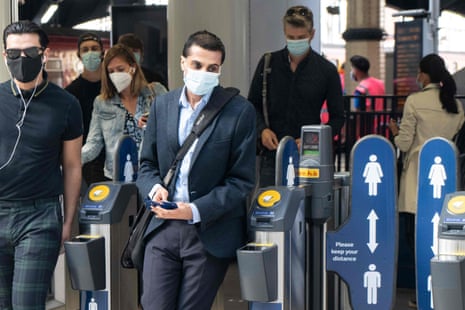 Commuters wearing face masks walk through the ticket barriers at Waterloo Station in London on June 15, 2020.