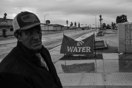 A sign reading water with a man in at hat in the foreground